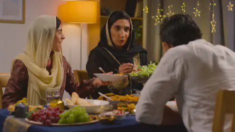 Muslim Muslim Family Sitting Around Table At Home Eating Meal To Celebrate Eid 2