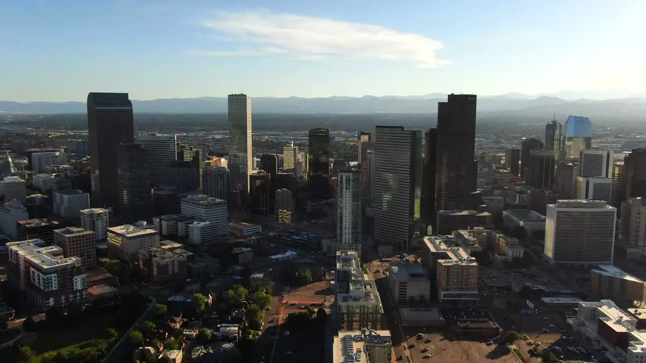 Aerial cinematic drone mid summer early fall Downtown Denver Colorado mile hight city buildings traffic wisp clouds blue sky afternoon sunset stunning golden hour light circling pan to the left motion