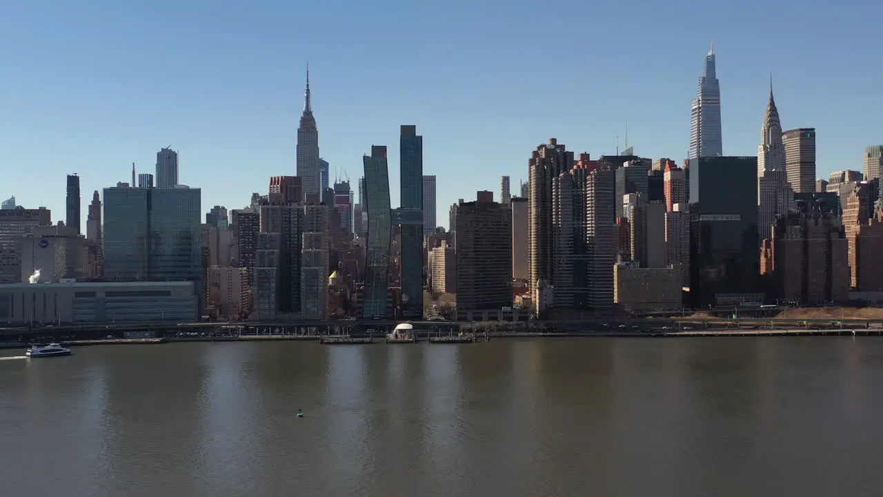 An aerial view over a calm East River on a sunny day with blue skies