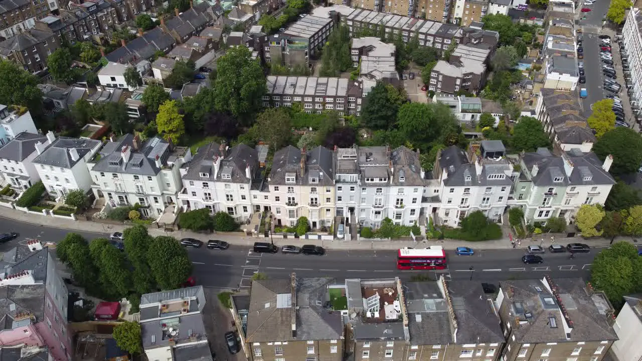 Red london bus passing row of terraced house Primrose hill London  drone aerial view