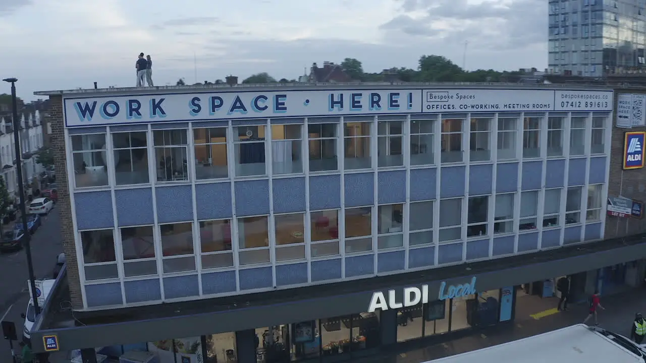 Orbiting aerial Workers chat on roof of building in Archway London UK