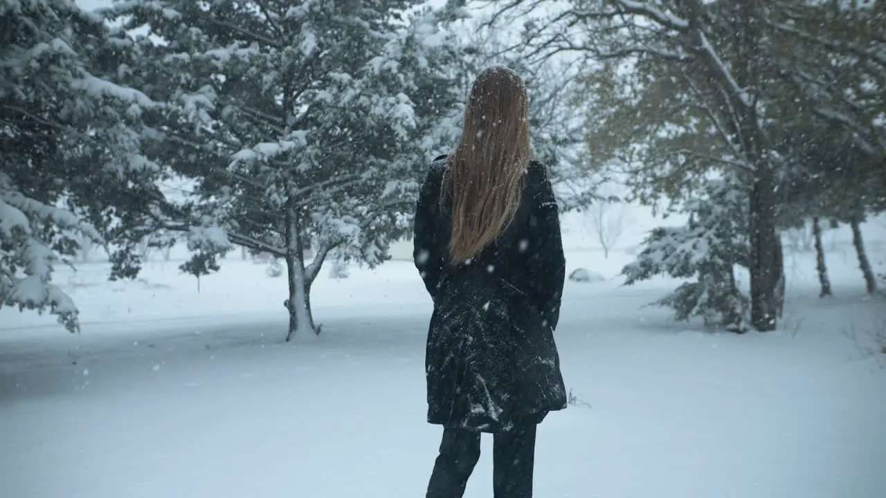 Woman walking outside in slow motion Christmas winter snow as snowflakes fall in cinematic slow motion