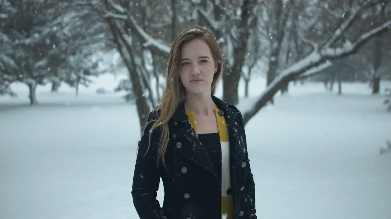 Happy woman outside in slow motion winter snow as snowflakes fall in cinematic slow motion