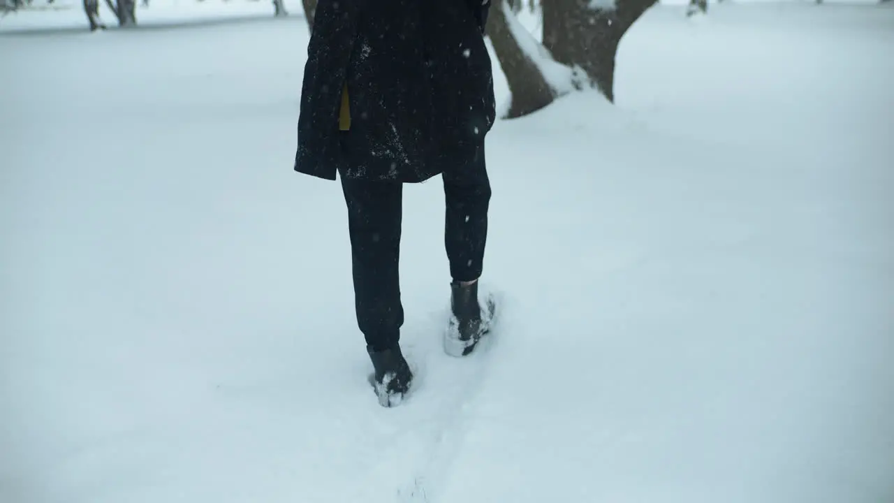 Woman walking outside in slow motion winter snow as snowflakes fall in cinematic slow motion