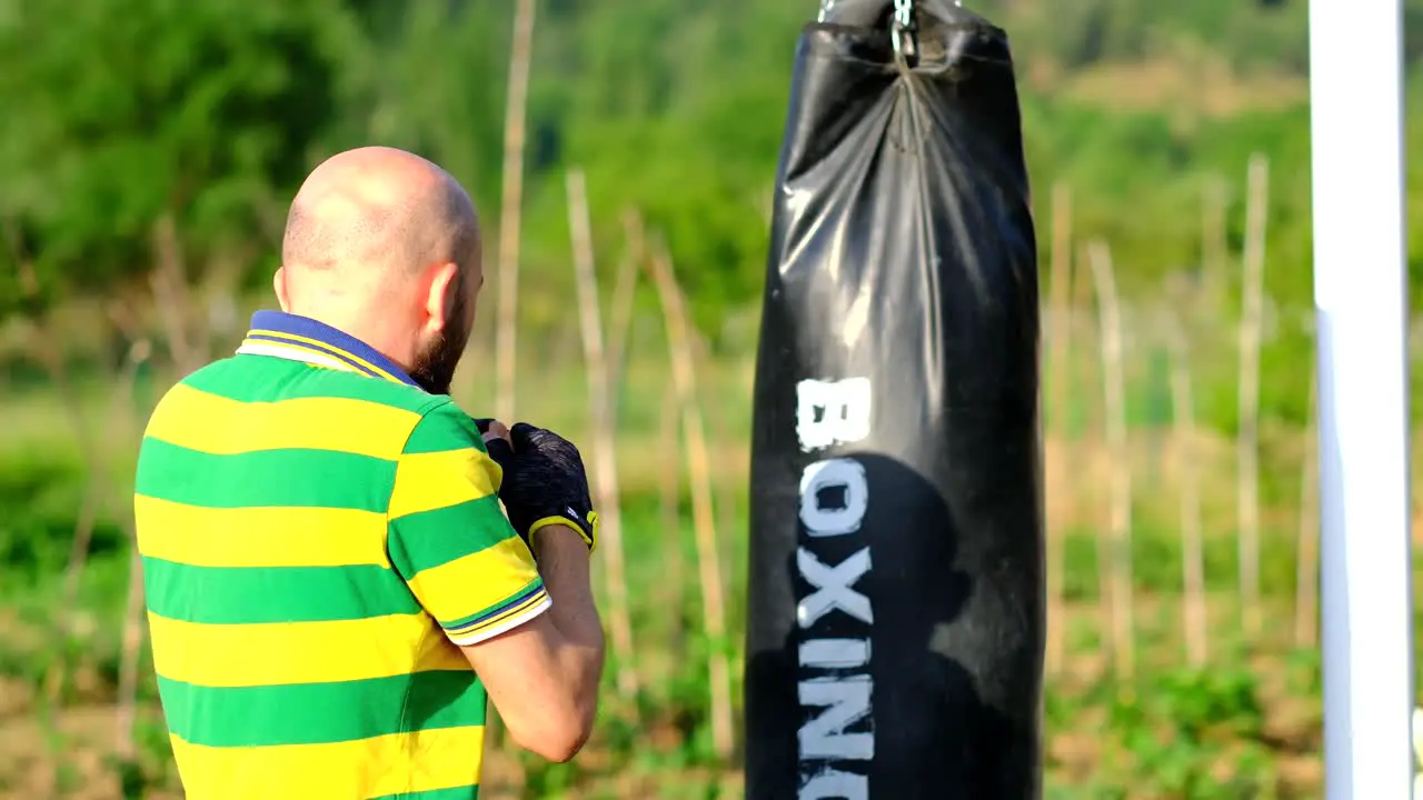 the athlete trains with a punching bag attached to a basketball hoop slow motion in nature