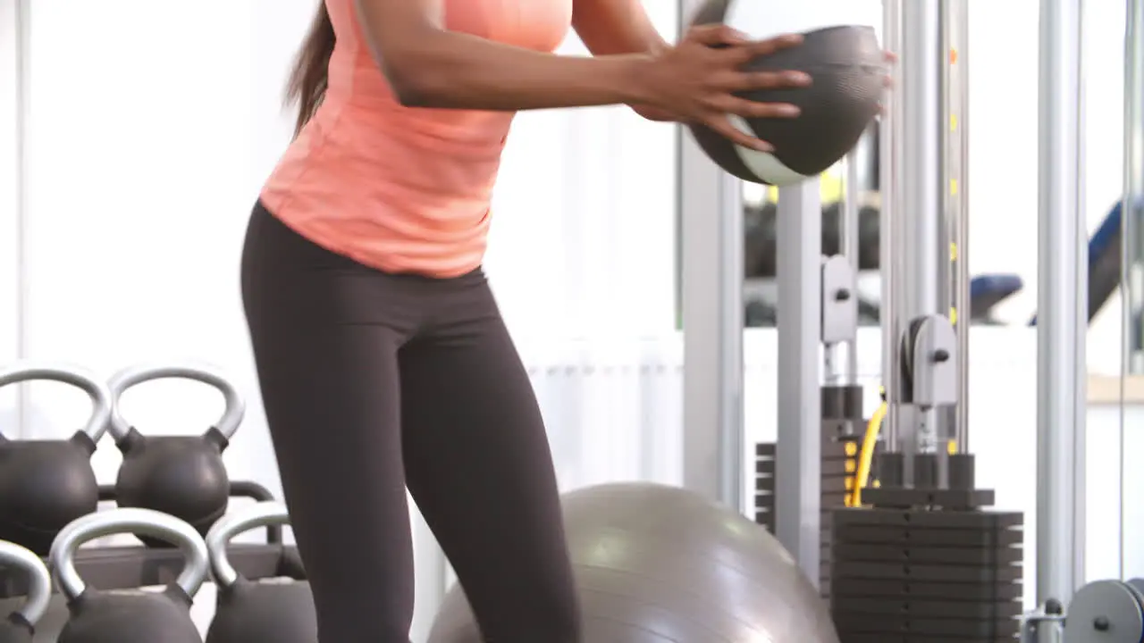 Young woman doing squats in a gym with a medicine ball