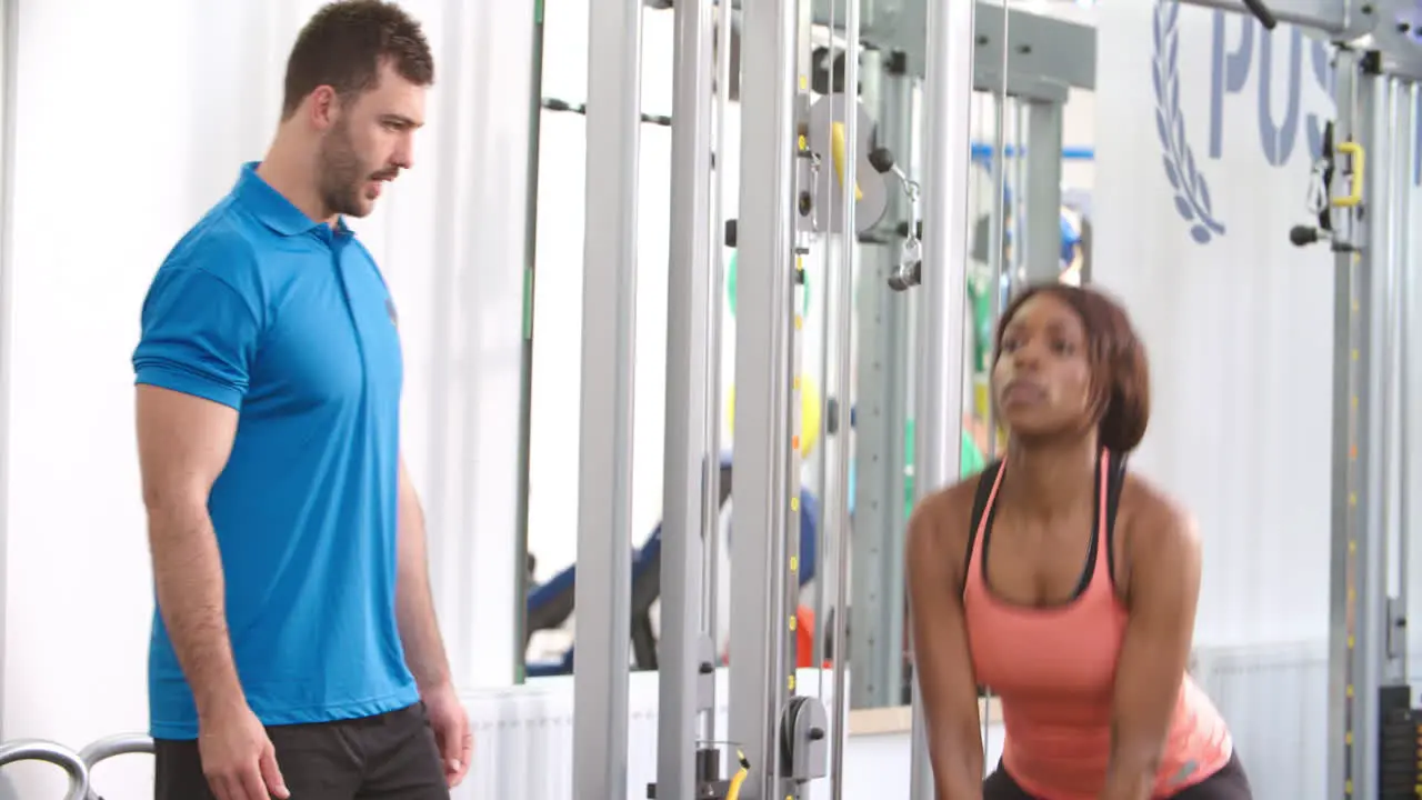 Woman using a kettlebell weight with a trainer in a gym