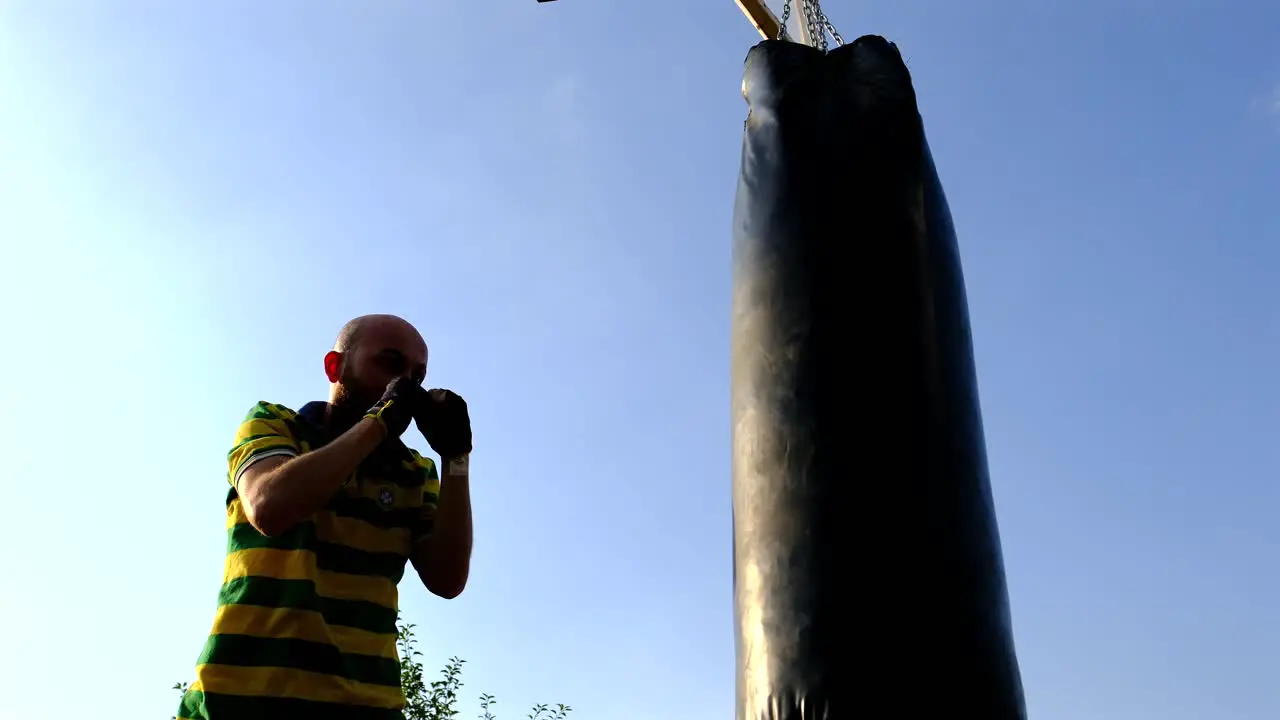 athlete trains with a punching bag attached to a basketball hoop in nature