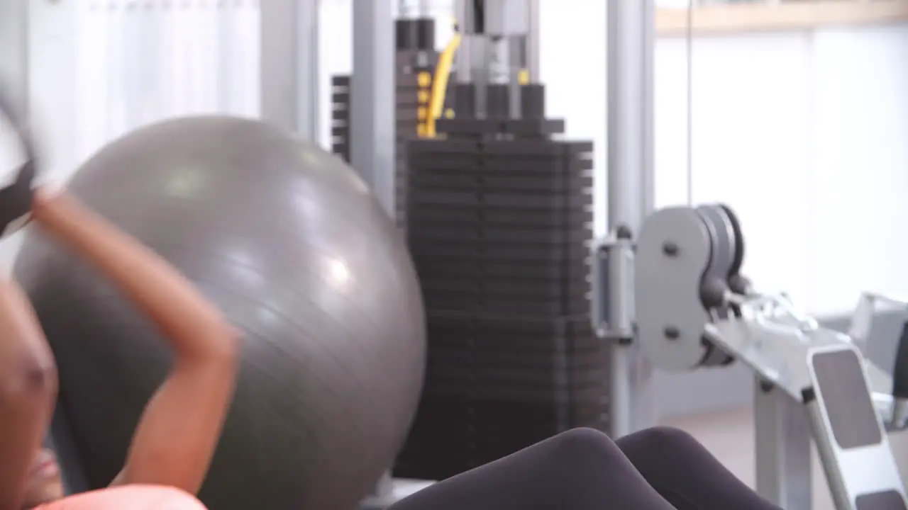 Woman doing sit-ups with a medicine ball in a gym close up