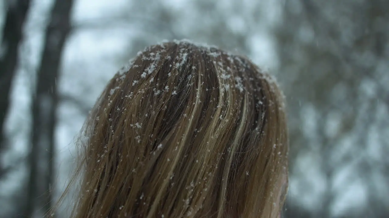 Slow motion snowflakes fall in woman's red hair