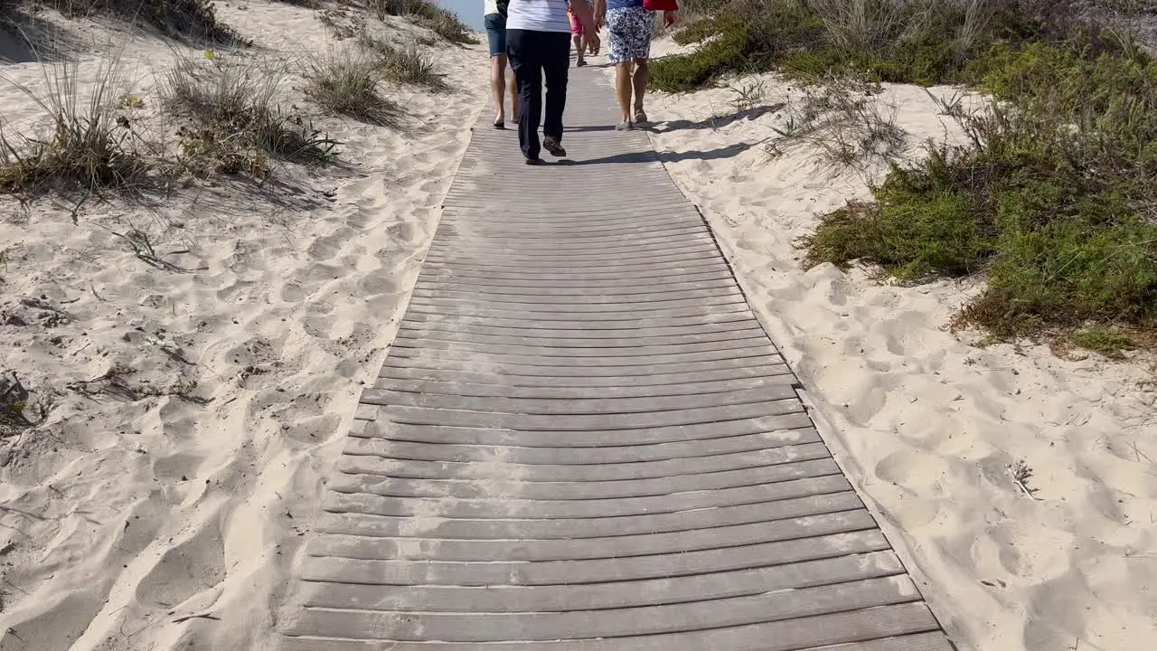 People walking on wooden path leading to beach in Lisbon Portugal