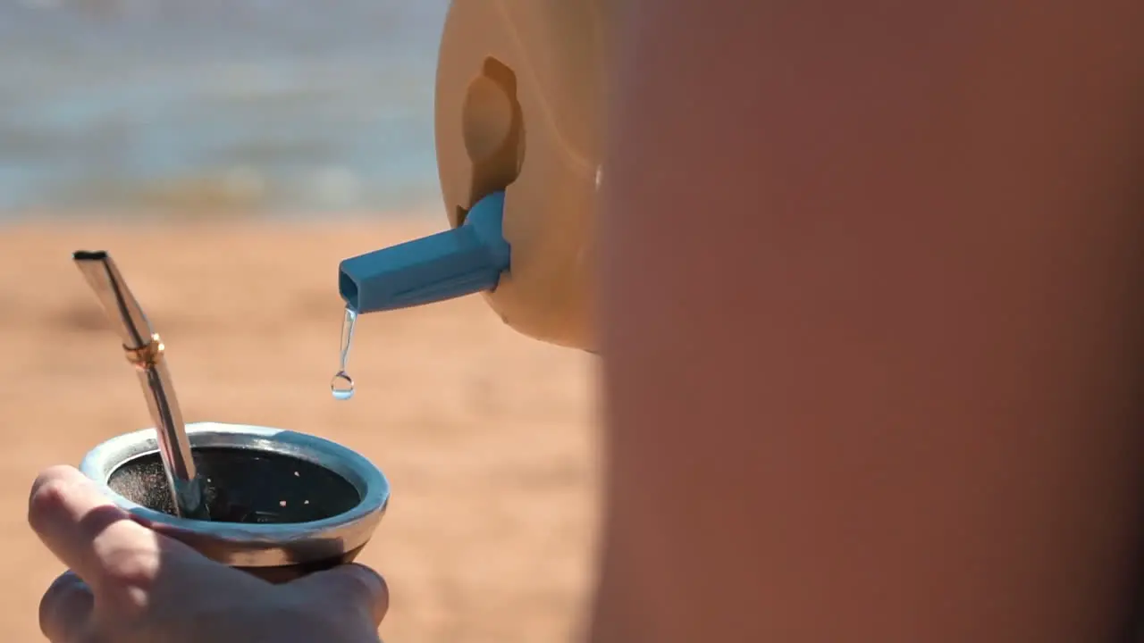 An image depicts the pouring of water into a traditional tereré gourd showcasing the cherished ritual of preparing and enjoying this refreshing South American drink