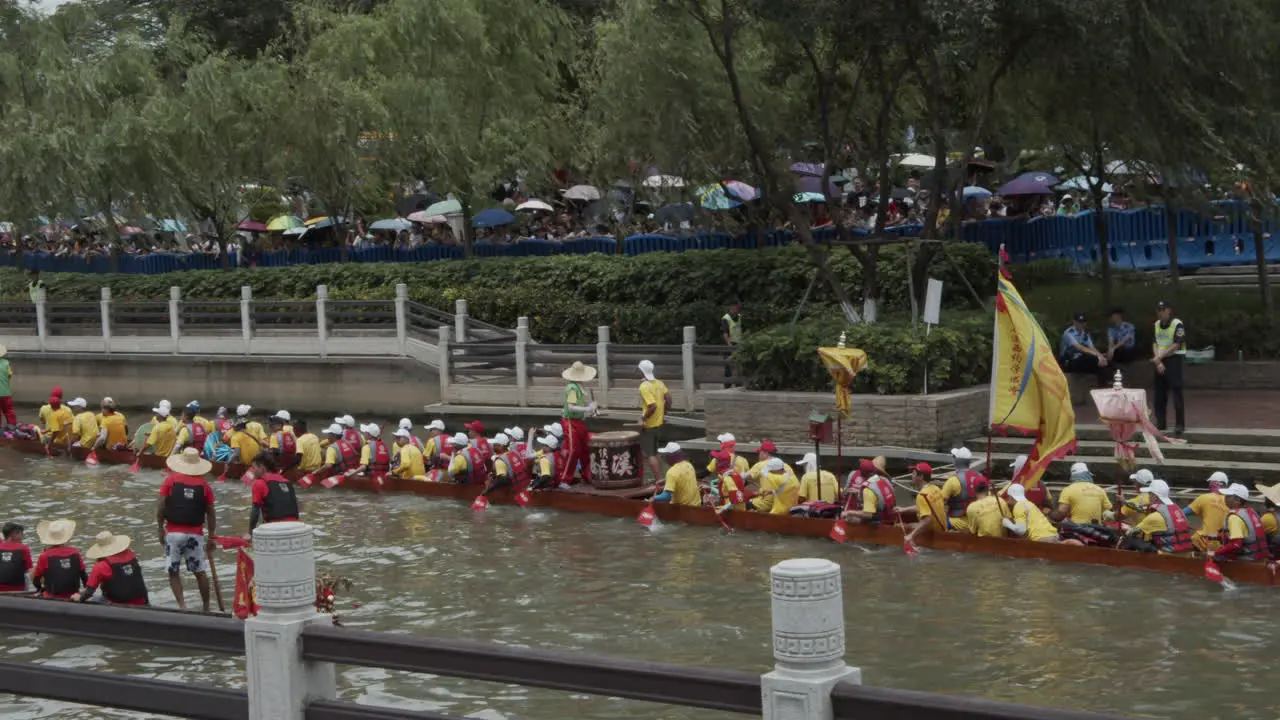 Chinese people dressed in yellow t-shirts paddle and hit drums on a dragon boat during dragon boat festival in Guangzhou Guangdong China