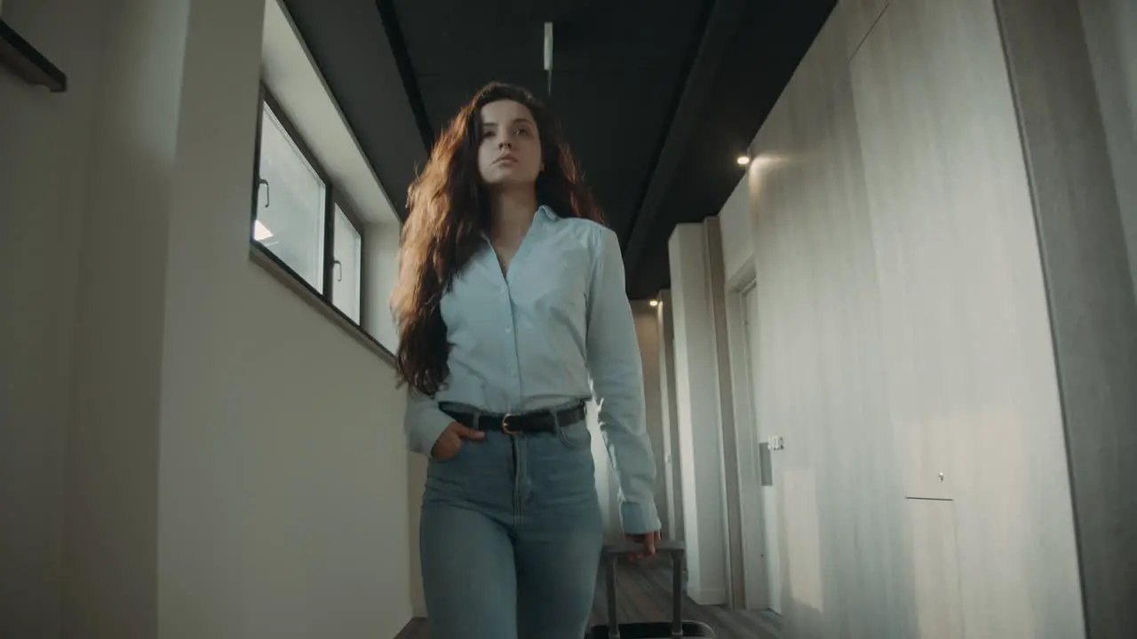 Arrogant woman with suitcase going corridor Girl looking around in hotel