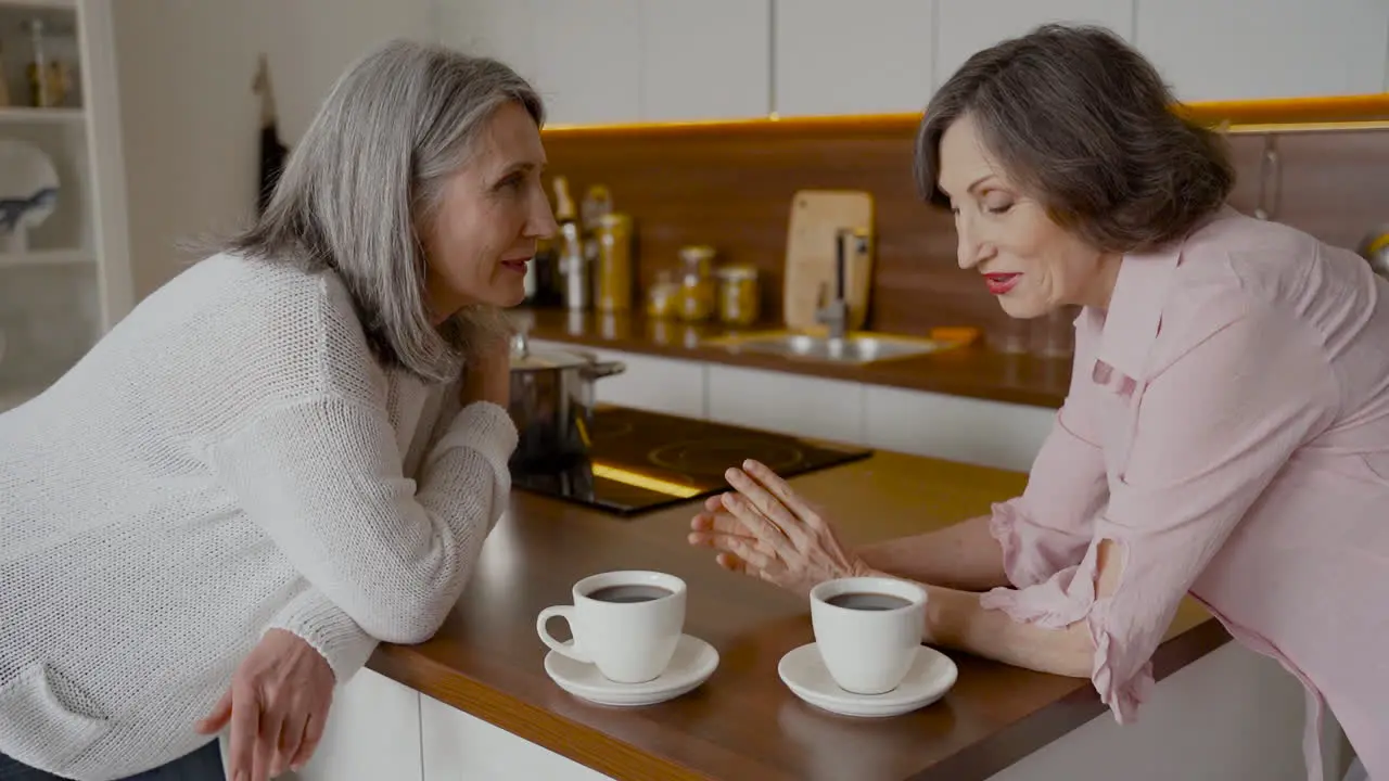 Zwei ältere Freundinnen Unterhalten Sich Beim Kaffeetrinken In Der Küche