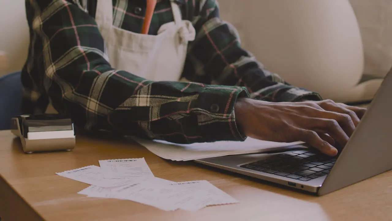 Close Up Of An Unrecognizable Coffee Shop Owner Sitting At Table And Calculating Finance Bill On Laptop Computer