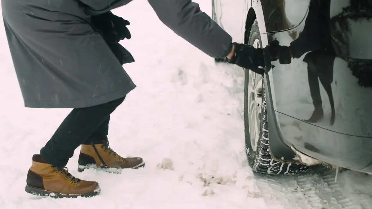 Close Up Of An Unrecognizable Man Checking Car Wheels During A Snowy Winter Day