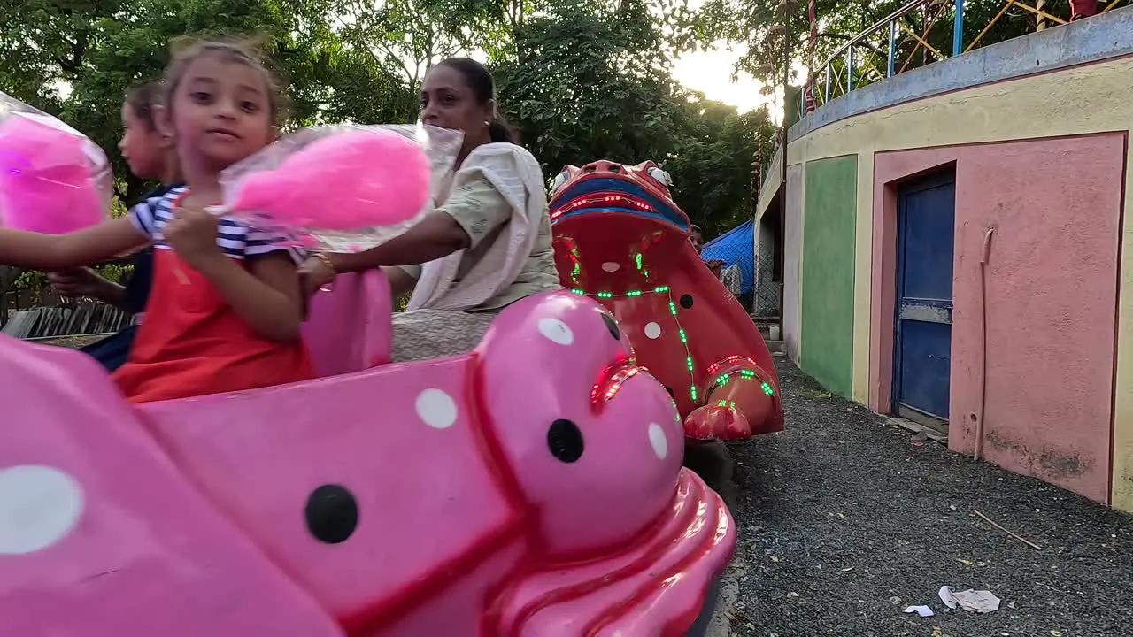 Small children enjoying the frog ride in the amusement park