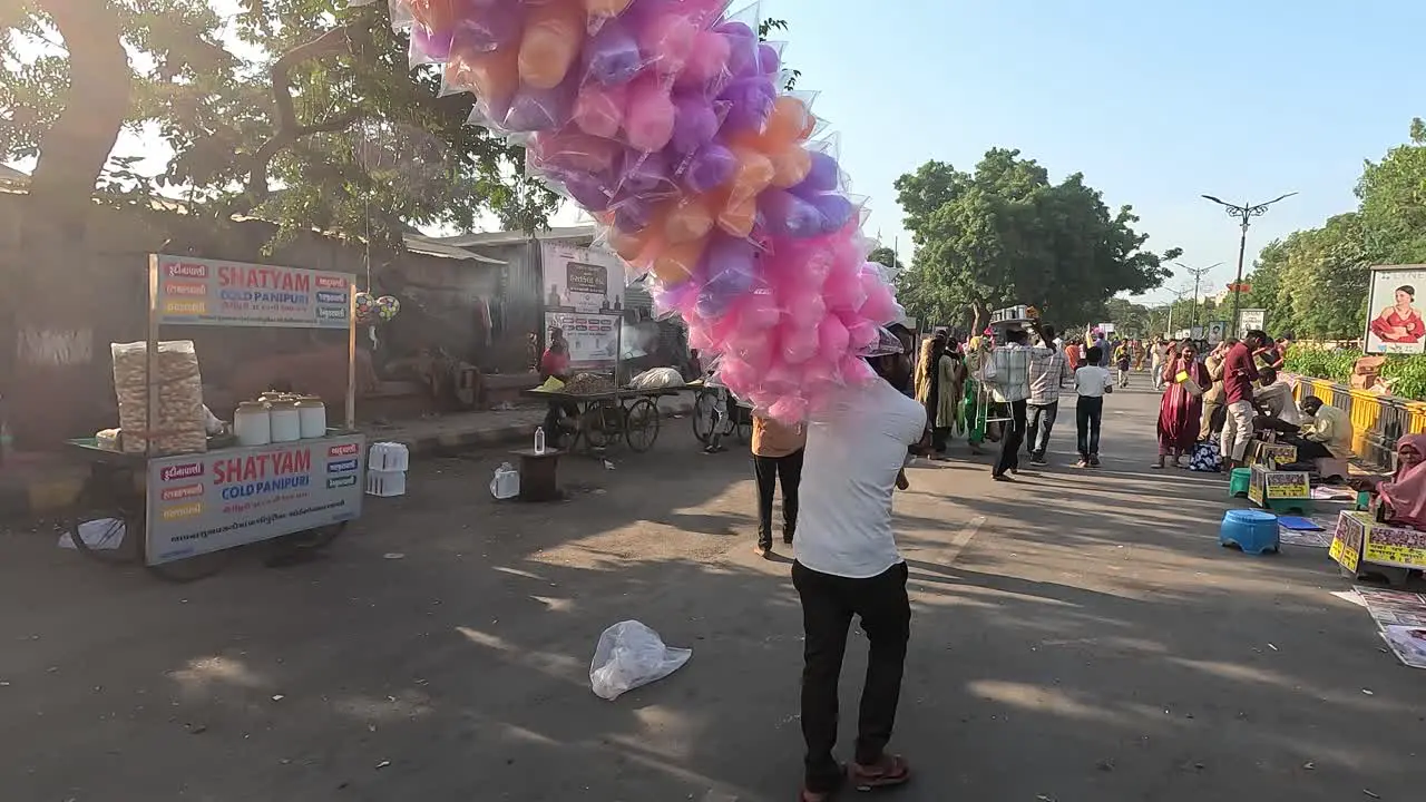 A shopkeeper is selling colorful and tasty cotton candy on the street road