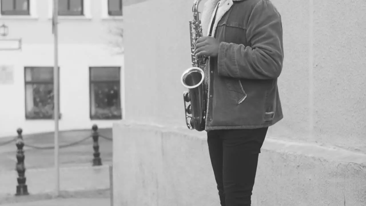 Schwarz-Weiß-Ansicht Eines Saxophonkastens Mit Münzen Auf Dem Boden Und Einem Mann In Jacke Der Auf Der Straße Saxophon Spielt