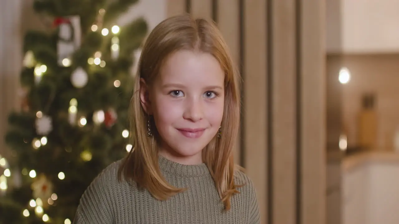 Vista Frontal De Una Chica Rubia Sonriendo A La Cámara En Una Habitación Decorada Con Un árbol De Navidad 1