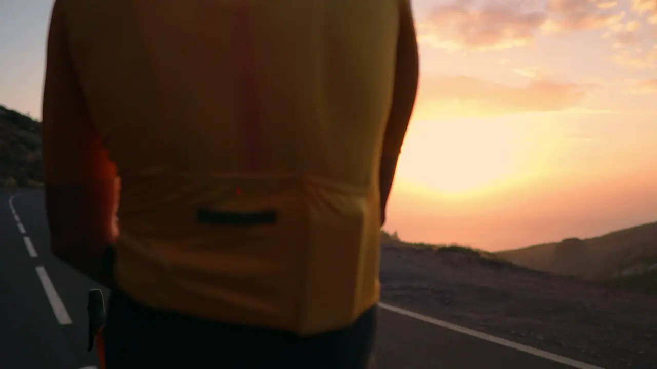 Un Joven Deportista En La Cima De Una Montaña Con Una Camiseta Amarilla Y Equipo Deportivo Descansa En Su Bicicleta Disfrutando De Las Vistas De Las Montañas Y Del Atardecer Después Del Entrenamiento