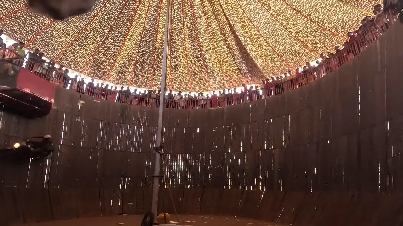 The well of death scene in which thousands of people watch the bikes and cars in the well of death the bikes and cars passing by the camera