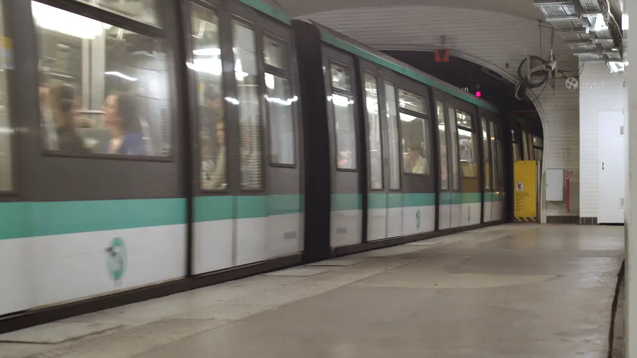 A full metro with people in Paris leaving the station and disappearing into the tunnel with one person waiting on the platform for the next train