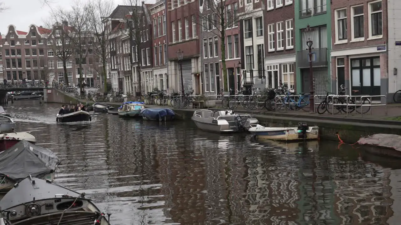 Motorboat with tourists moving down the city canal in Amsterdam