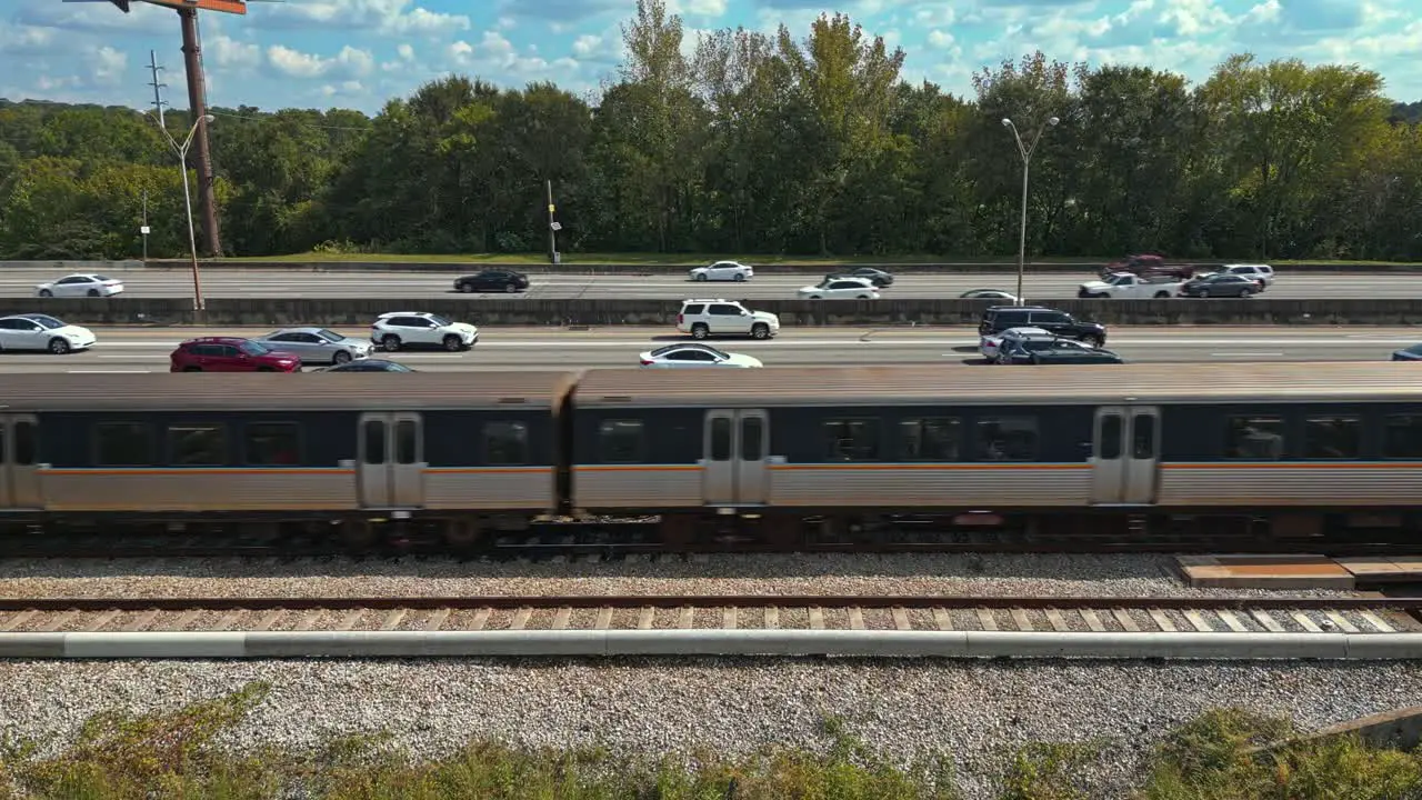 Epic aerial view of passenger trains crossing parallel to highway Atlanta city road traffic GA USA