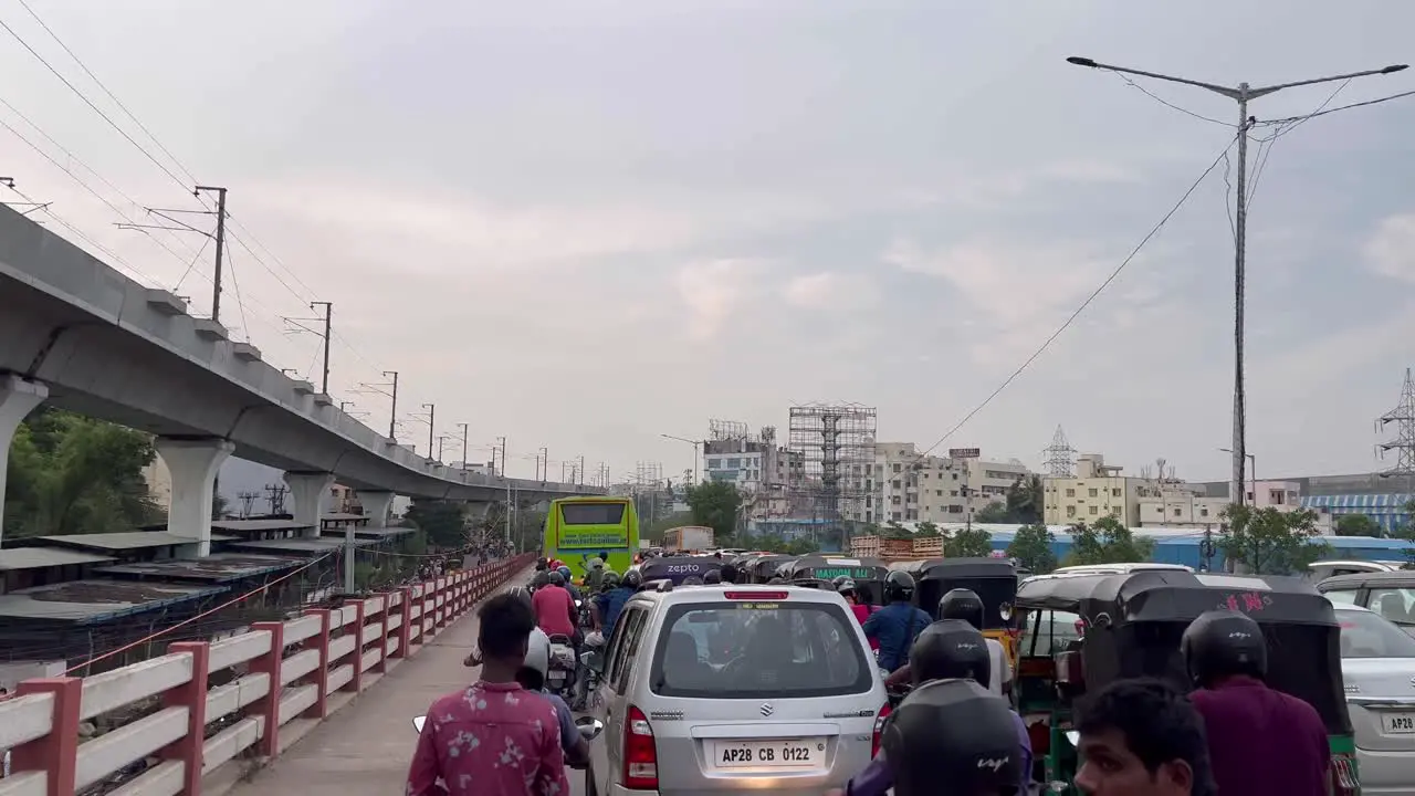 Several buses vehicles and bikes are snarled in traffic and a isolated flyover passes through the city