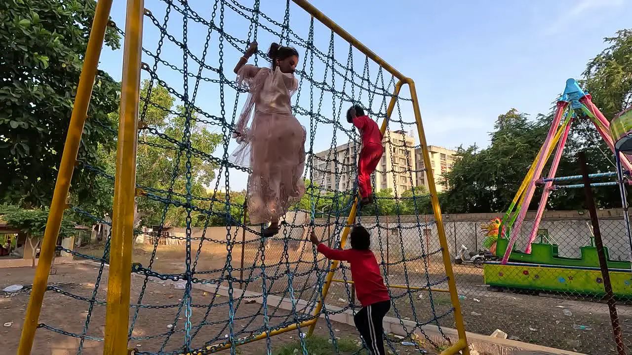 Little kids are climbing the chain with both hands and feet and playing army and police games