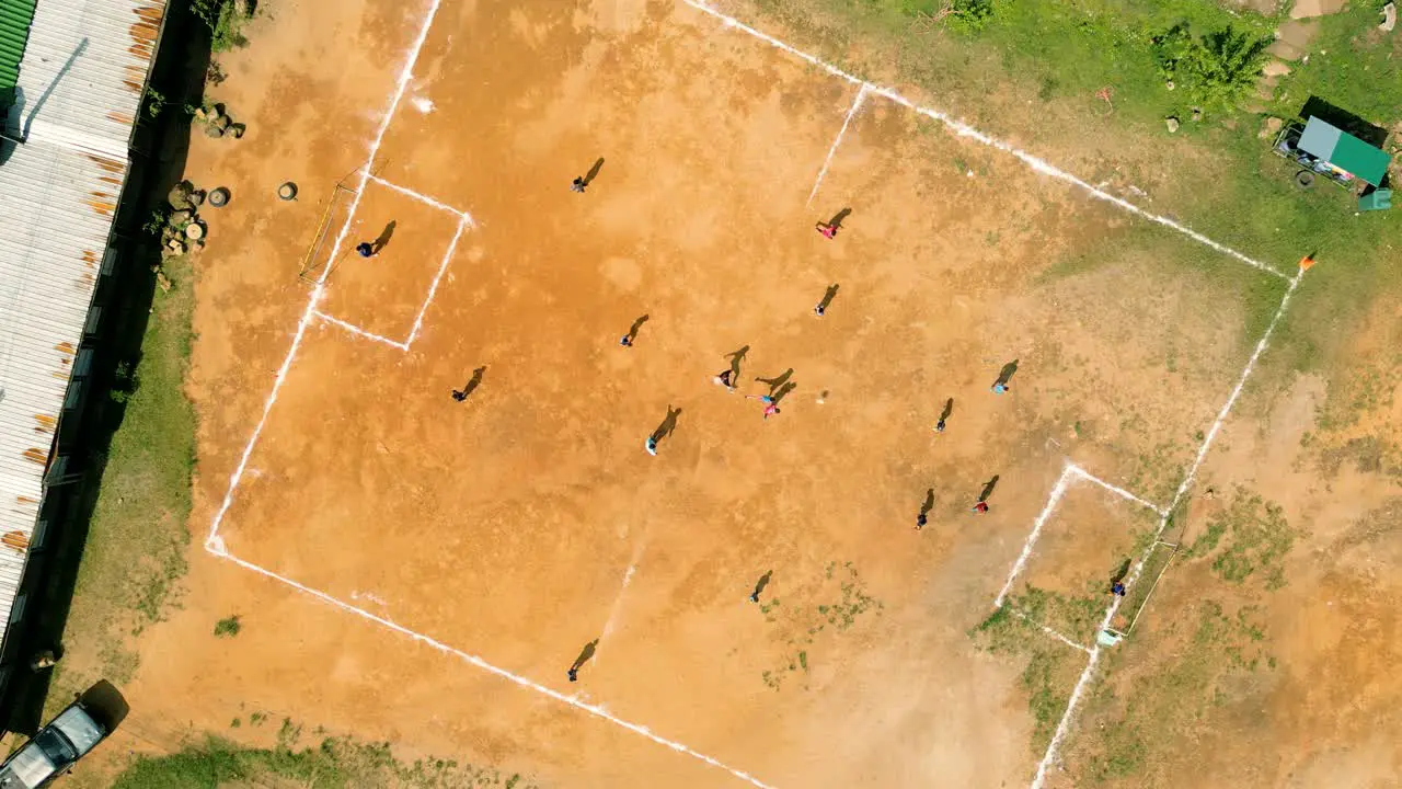 4K Cinematic sport aerial drone footage of children playing on a footbal field in the mountain village of Doi Pui next to Chiang Mai Thailand on a sunny day