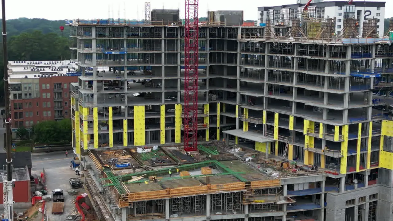 Aerial slide and pan shot of extensive construction site of modern tall apartment building