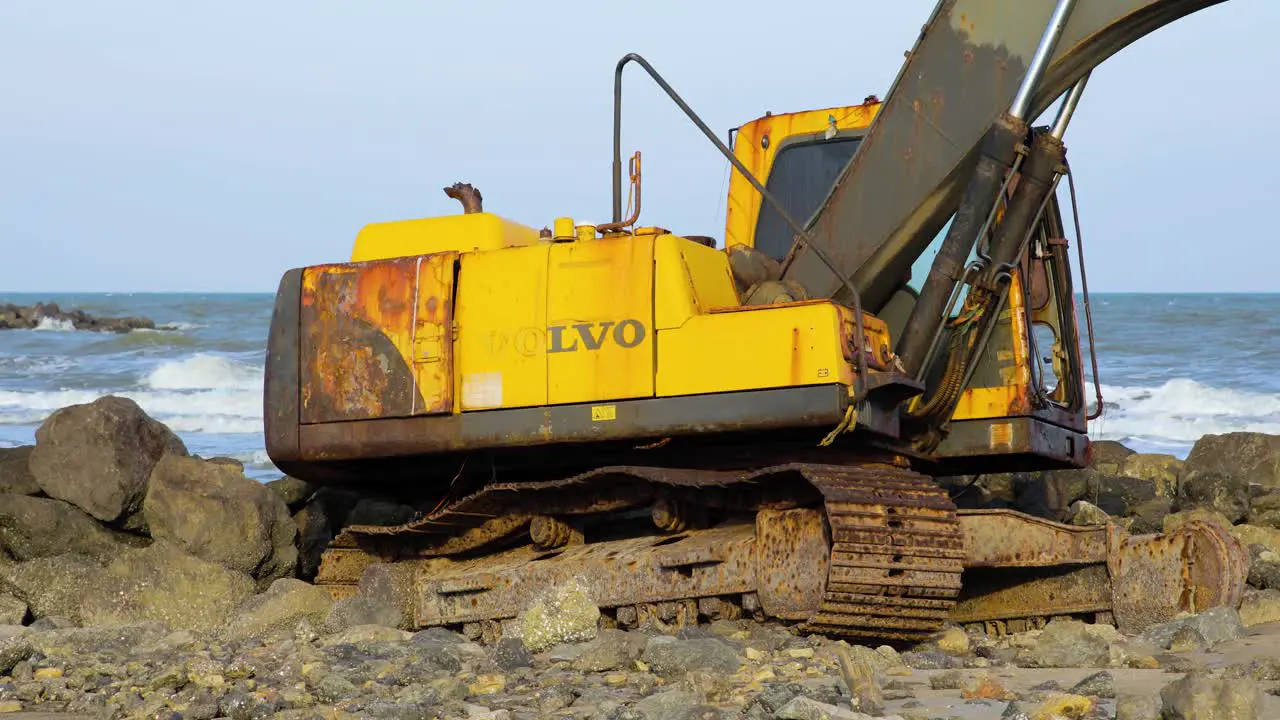 Abandoned Yellow Digger on Rocky Beach in Thailand