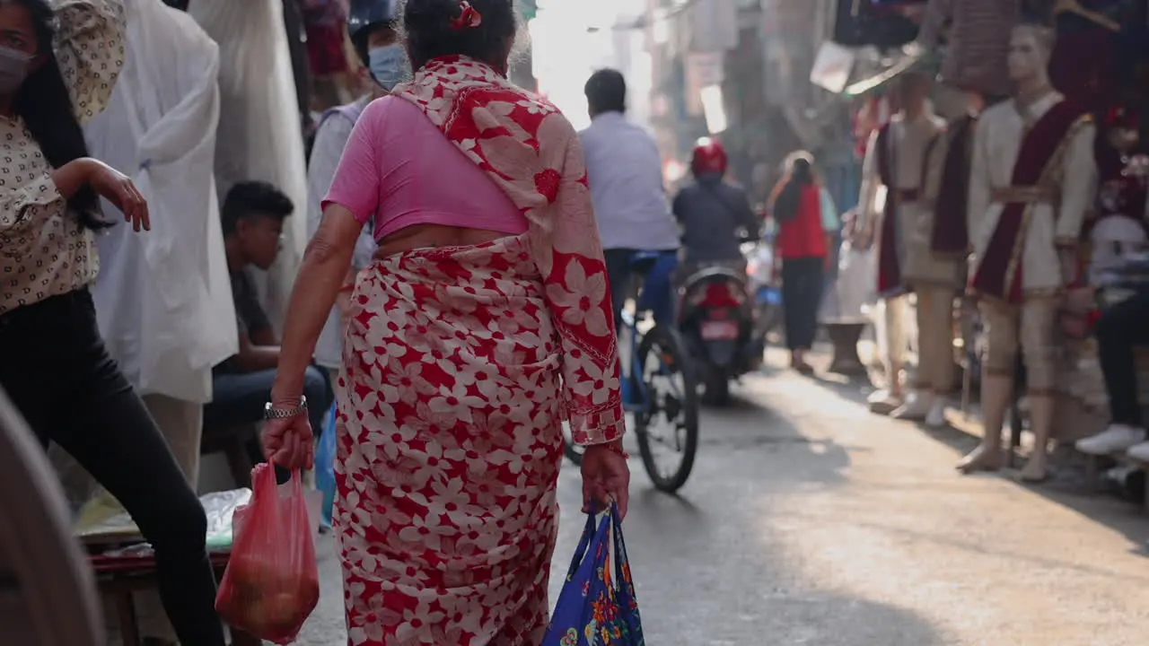 Slow motion following a woman dressed in a sari walking through the streets of Kathmandu Nepal