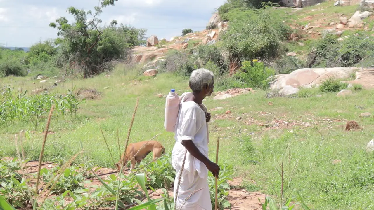 Old Tribal shepherd or sheepherder man with water bottle and stick in mountain at India during the hot sunny day