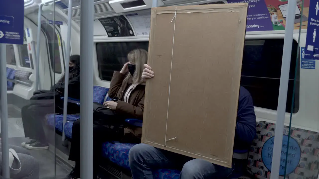 View Of Male Holding Large Art Frame Canvas On Jubilee Train In London 17 March 2022