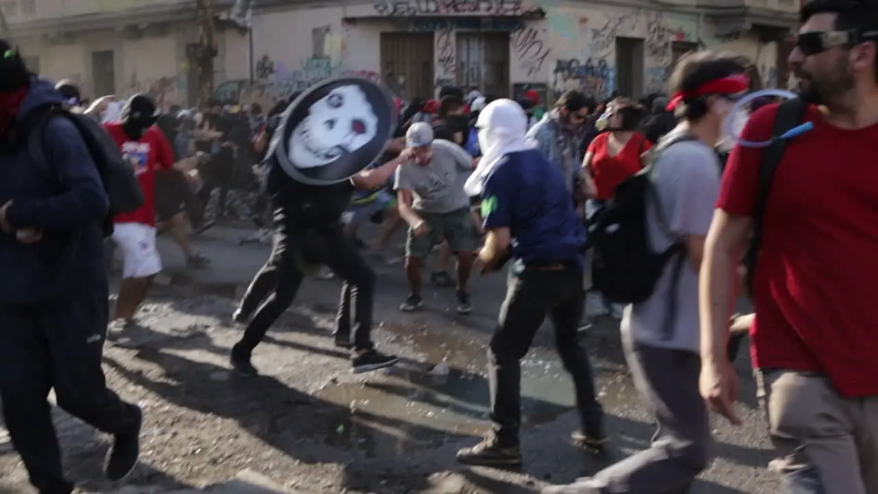 Rioters panic and flee through the narrow streets of Santiago