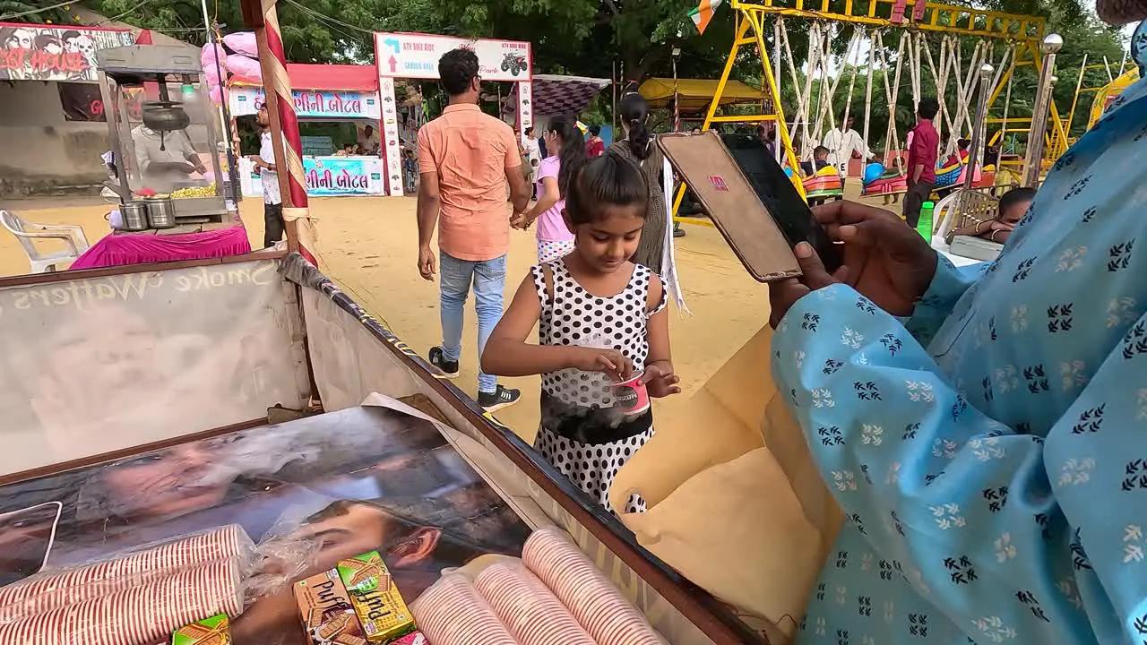 A little girl is eating Ness Cafe Ice Cube Biscuits at the fair and puffing and enjoying