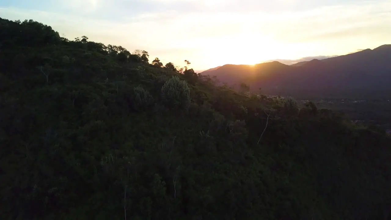 Aerial shot coming from behind a mountain to reveal the picturesque beach town of Baleia in São Sebastião Brazil at sunset