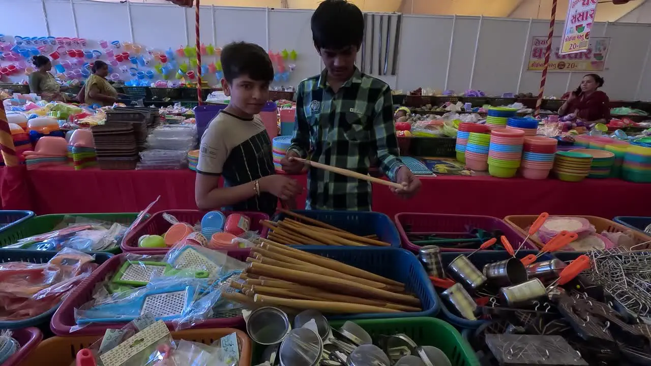 Two young boys are buying utensils from the sale