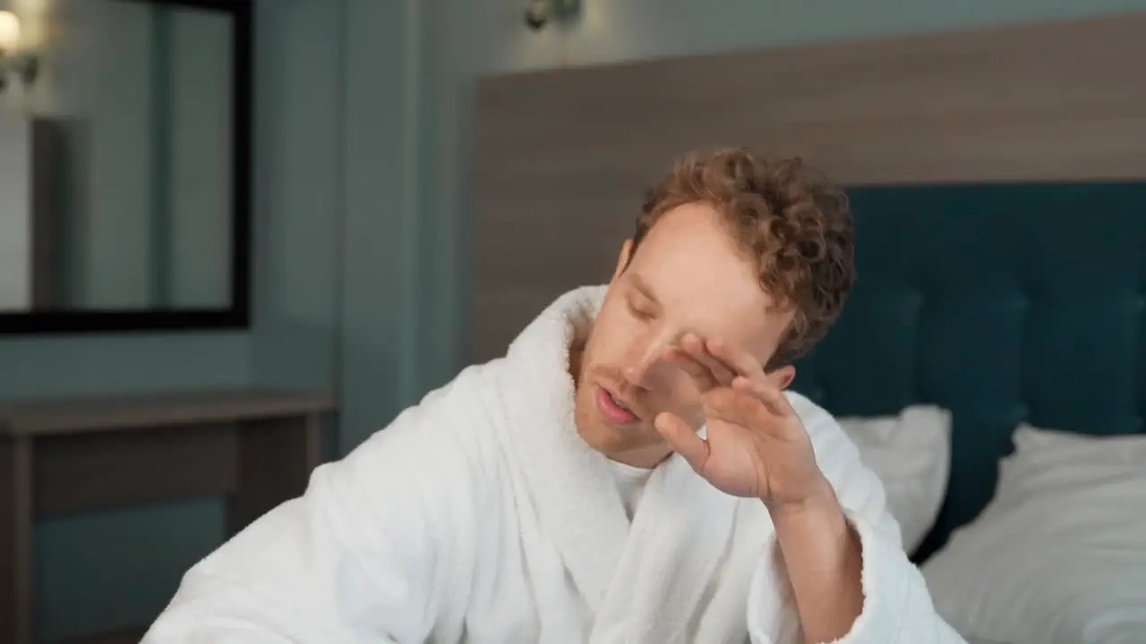 A young man in bed measures the temperature with an electronic non-contact thermometer