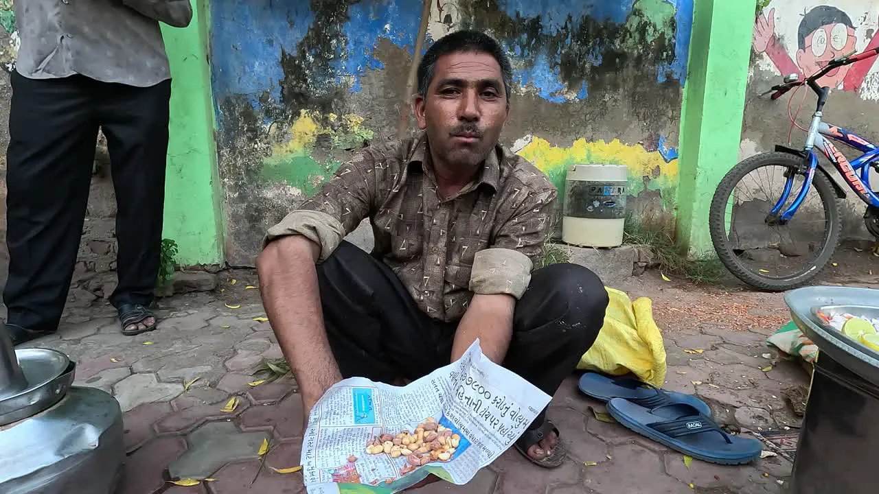 A man enjoys sitting on the ground and eating corn on the ground during a holiday