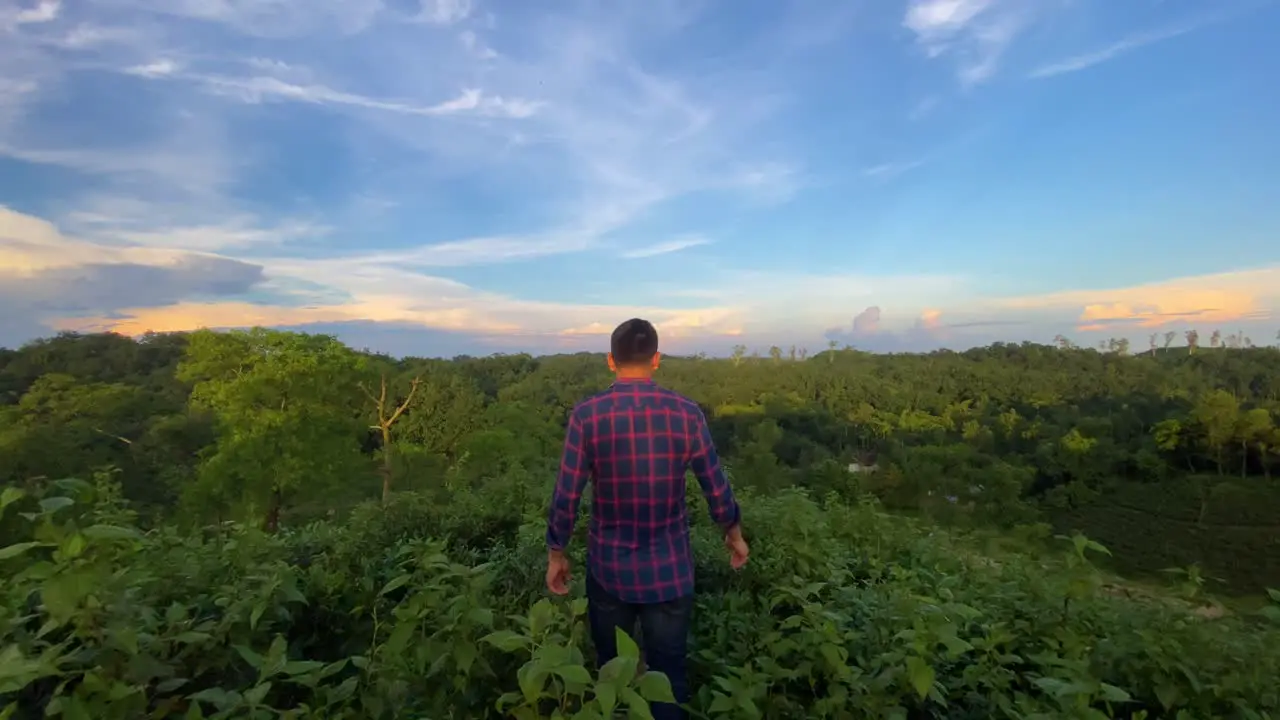 Young guy enjoying nature over hilltop at morning with dramatic sky