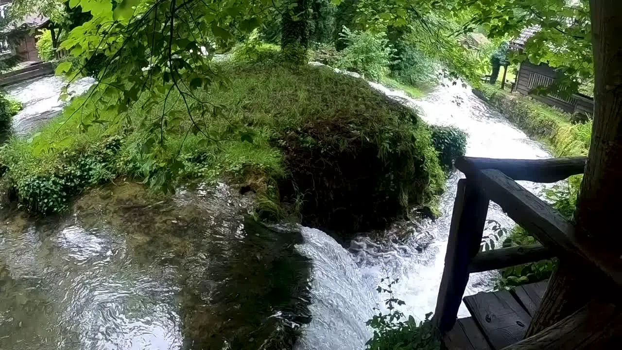 Small waterfalls separated by green patch of land shot from a wooden structure