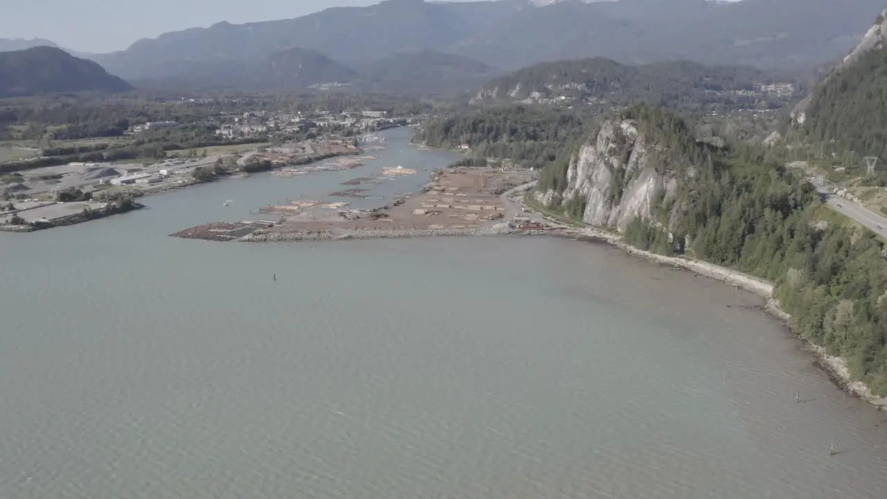 Aerial fly over ocean mineral bay harbor of lumber industry export dock of inventory stacked for preperation to board tug boats to the freightor port of cargo transportaion on a clear summer day 1-4