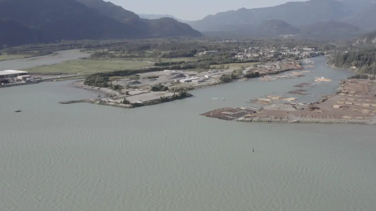 Aerial fly over ocean mineral bay harbor of lumber industry export dock of inventory stacked for preperation to board tug boats to the freightor port of cargo transportaion on a clear summer day 2-4