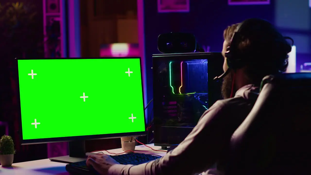 Professional gamer using chroma key PC desktop to complete levels in game talking with friends