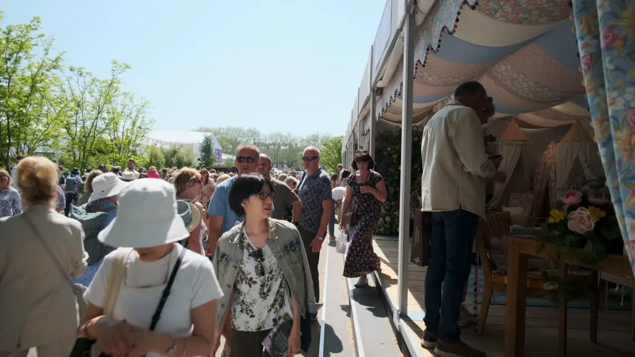 People walking past flowery shop stalls at the Chelsea flower show